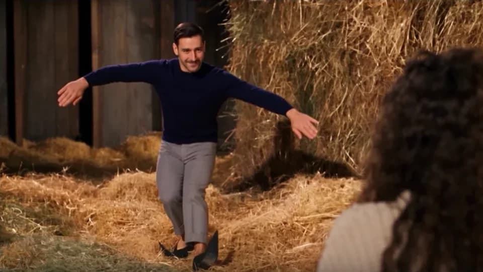 A dancer tiptoes in a rustic barn while a seated observer watches in a generated video example